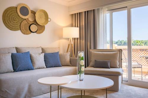 Suite con cama extragrande, sofá cama, balcón y vistas al complejo del hotel Denia la Sella Golf Resort and Spa