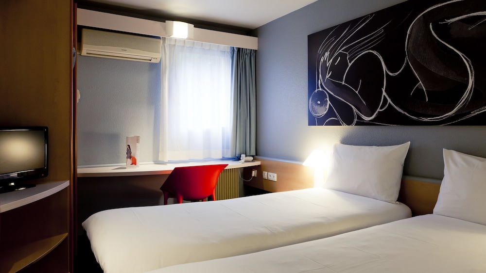 Habitación con dos camas individuales equipada con nueva ropa de cama del hotel Ibis Lyon Nord. Foto 1
