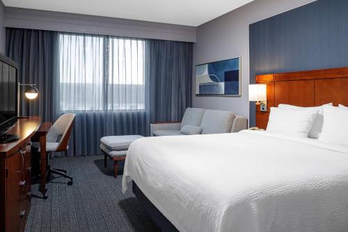 Habitación con cama extragrande y sofá cama del hotel Courtyard By Marriott Long Island Macarthur Airport