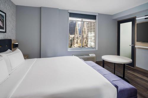 Habitación con cama extragrande y vistas parciales a lugares de interés del hotel DoubleTree by Hilton New York Midtown Fifth Ave. Foto 5