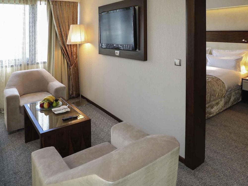 Suite Junior con cama king size y sofá; lado del río, salón independiente; Jacuzzi del hotel Movenpick Sarajevo. Foto 1