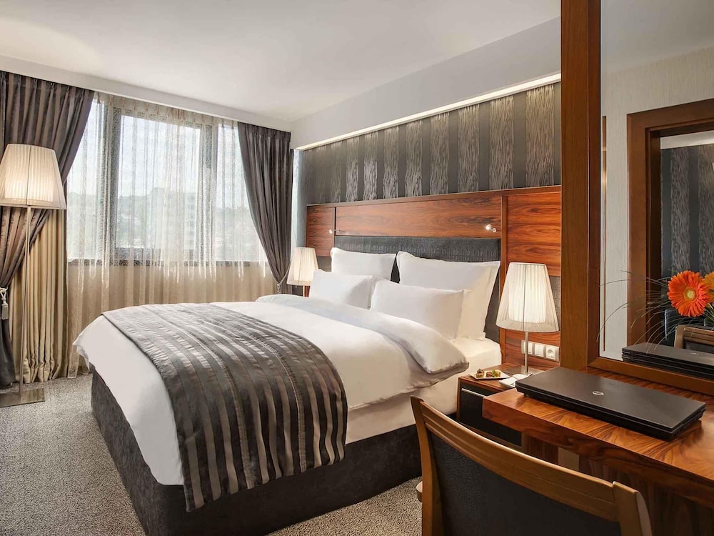 Suite Junior con cama king size y sofá; lado del río, salón independiente; Jacuzzi del hotel Movenpick Sarajevo. Foto 2