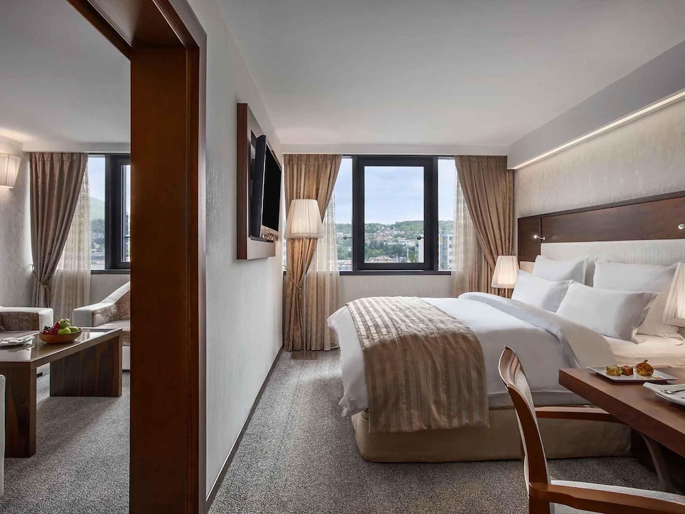 Suite Junior con cama king size y sofá; lado del río, salón independiente; Jacuzzi del hotel Movenpick Sarajevo. Foto 3