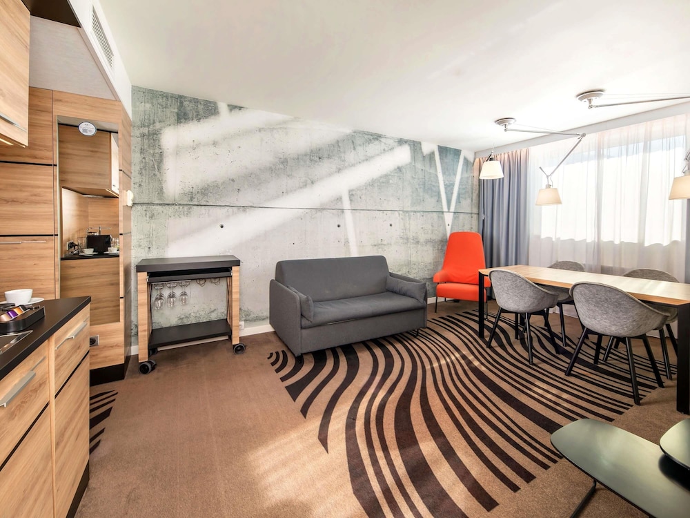 Suite Superior con cama grande, sofá y cocina del hotel Novotel Krakow City West. Foto 3