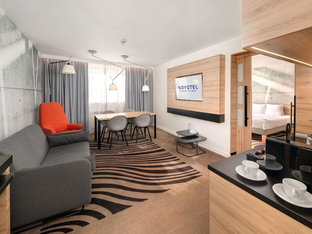 Suite Superior con cama grande, sofá y cocina del hotel Novotel Krakow City West. Foto 7