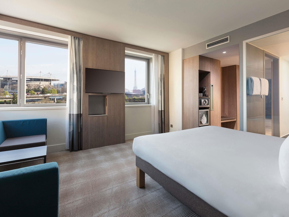 Habitación Deluxe con 1 cama doble, sofá y vistas a la torre Eiffel del hotel Novotel Paris Saint Denis Stade Basilique