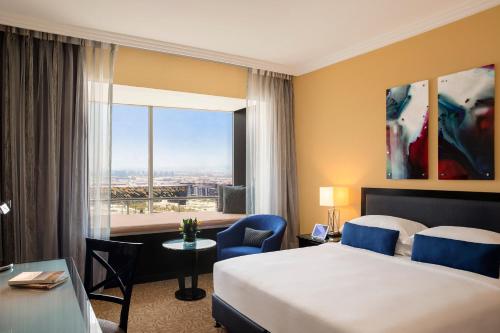 Habitación con cama extragrande y acceso al salón del hotel Towers Rotana