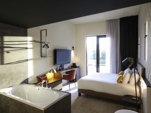 Suite Junior con 1 cama king size, bañera de hidromasaje, acceso a la terraza y vistas al río del hotel Mercure Namur. Foto 1