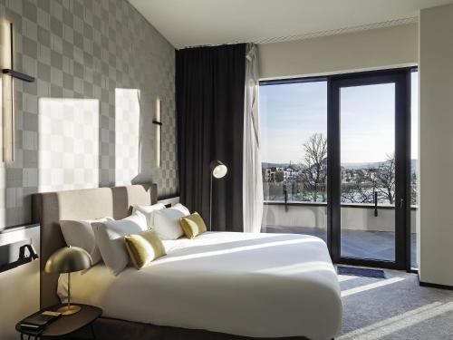 Suite Junior con 1 cama king size, bañera de hidromasaje, acceso a la terraza y vistas al río del hotel Mercure Namur. Foto 4