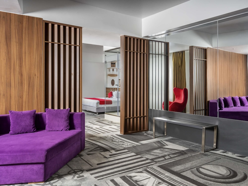 Suite Privilege con una cama doble y sofá del hotel Mercure Bucharest Unirii. Foto 1