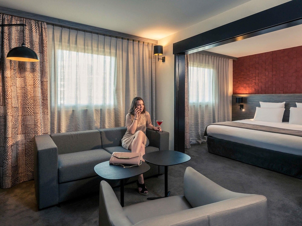 Suite con cama doble y sofá del hotel Mercure Paris Porte De Pantin