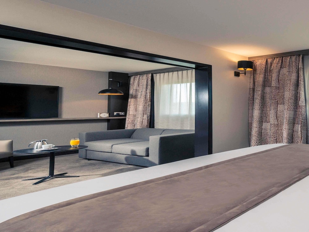 Suite con cama doble y sofá del hotel Mercure Paris Porte De Pantin. Foto 1