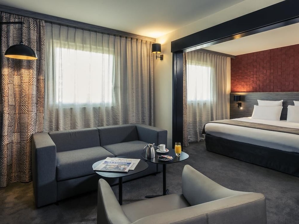 Suite con cama doble y sofá del hotel Mercure Paris Porte De Pantin. Foto 3