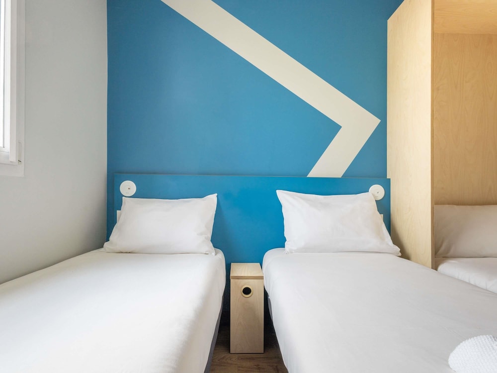 Habitación con dos camas individuales y una cama abatible del hotel Ibis Budget Nanterre La Defense