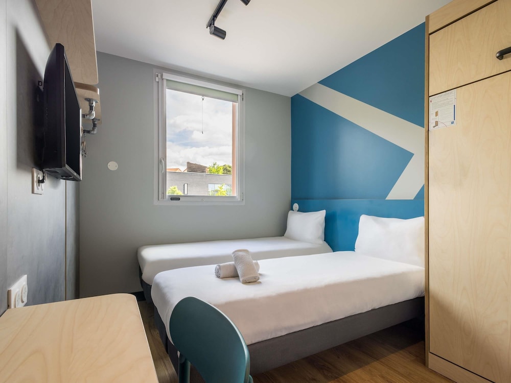 Habitación con dos camas individuales y una cama abatible del hotel Ibis Budget Nanterre La Defense. Foto 1