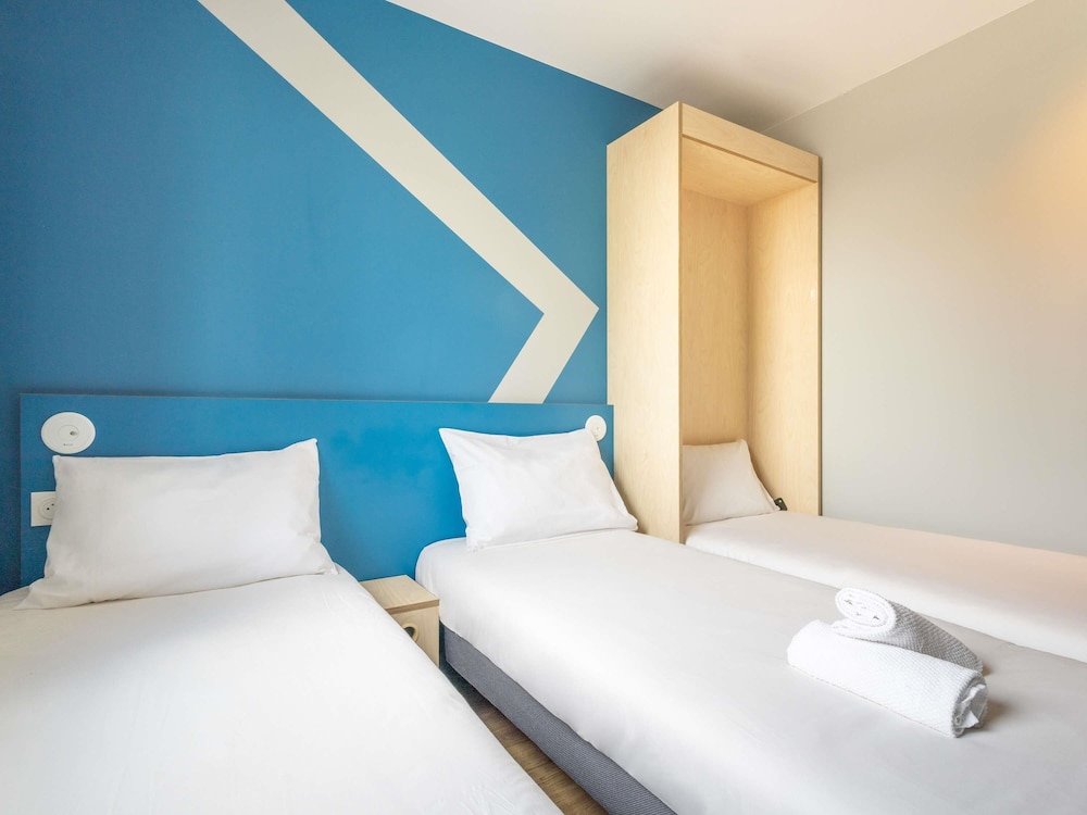 Habitación con dos camas individuales y una cama abatible del hotel Ibis Budget Nanterre La Defense. Foto 2