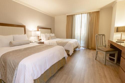 Suite de 1 dormitorio con 2 camas dobles y sofá cama del hotel Antaris Cintermex