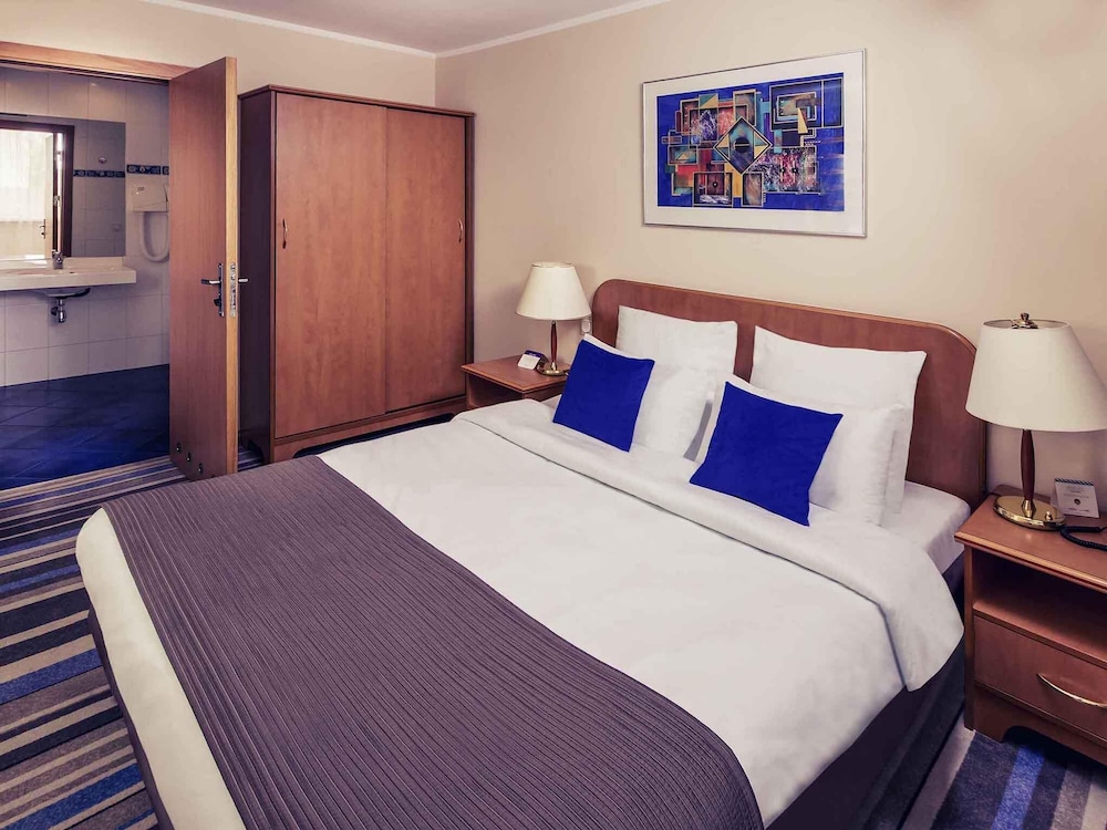 Suite Deluxe con una cama grande y un sofá del hotel Mercure Torun Centrum. Foto 1