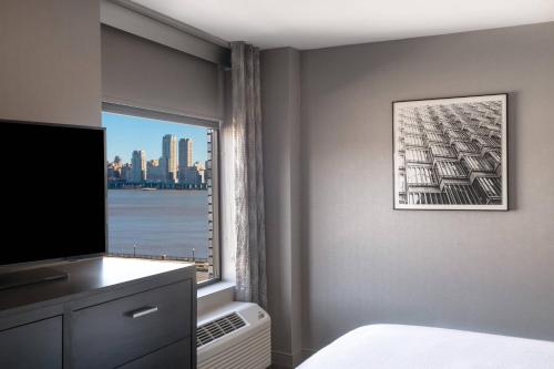 Suite más amplia con 1 dormitorio, 1 cama extragrande, sofá cama y vistas parciales a la ciudad del hotel Residence Inn Weehawken Port Imperial. Foto 5