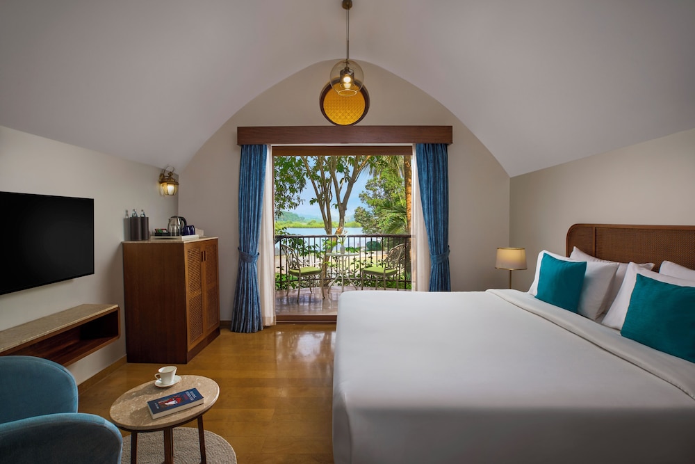Habitación Villa con cama doble, acogedora zona de estar con vistas al jardín y al río del hotel Mercure Goa Devaaya Resort