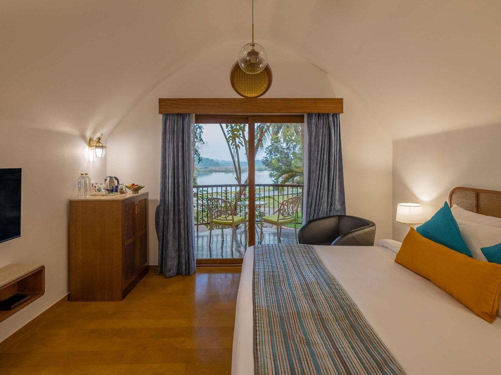 Habitación Villa con cama doble, acogedora zona de estar con vistas al jardín y al río del hotel Mercure Goa Devaaya Resort. Foto 1