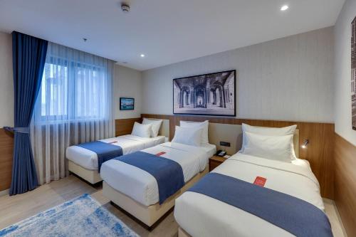 Habitación Executive, tres camas individuales y sofá cama del hotel Ramada By Wyndham Istanbul Old City. Foto 1