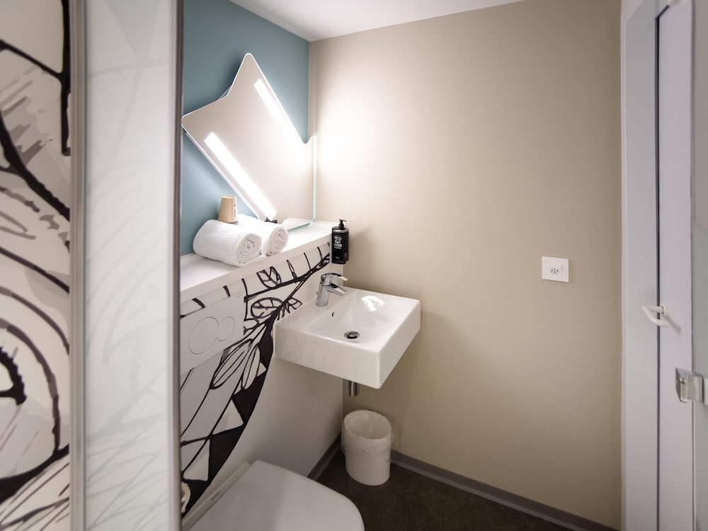 Habitación con camas individuales y baño cómodo del hotel ibis budget Fribourg. Foto 2
