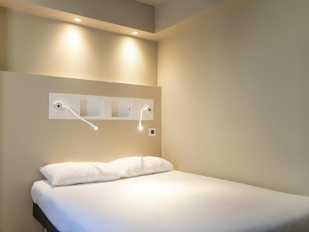 Habitación doble con cama doble, mesa y baño con todas las comodidades del hotel ibis budget Fribourg