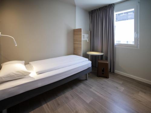 Habitación individual con cama individual, mesa y baño con todas las comodidades del hotel ibis budget Fribourg. Foto 2
