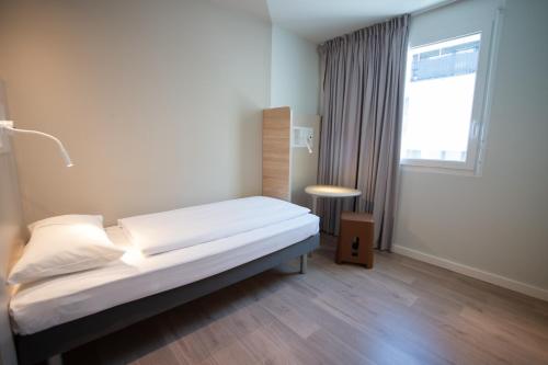 Habitación individual con cama individual, mesa y baño con todas las comodidades del hotel ibis budget Fribourg. Foto 9