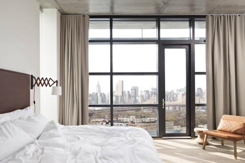 Habitación de esquina con cama extragrande y balcón con vistas a Manhattan del hotel The Boro