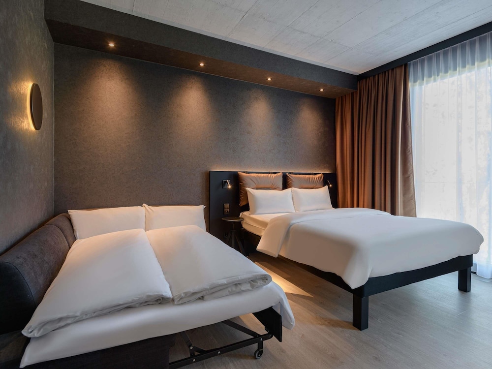 Habitación Confort Espacio Plus ALL con cama doble, sofá - cama y cocina del hotel Ibis Styles Friedrichshafen. Foto 6