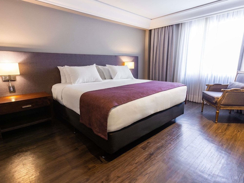 Suite Luxury con 1 cama king size, sofá cama y bañera de inmersión del hotel Grand Mercure Curitiba Rayon. Foto 1