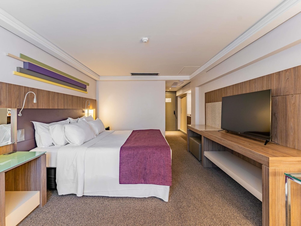 Suite Luxury con 1 cama king size, sofá cama y bañera de inmersión del hotel Grand Mercure Curitiba Rayon. Foto 11