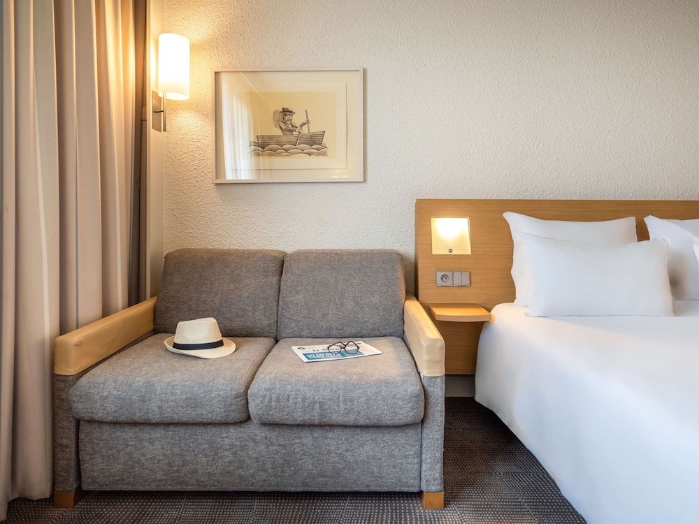 Suite con una cama doble y un sofá cama individual del hotel Novotel Paris Rueil Malmaison. Foto 1