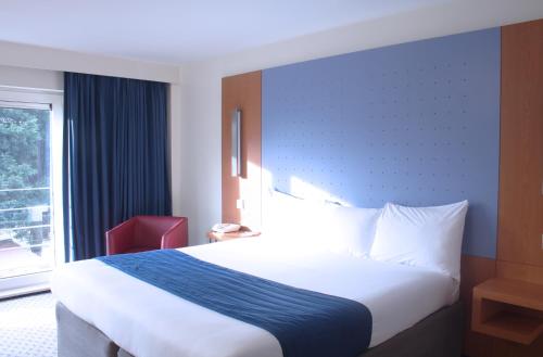 Habitación familiar con una cama doble y dos camas plegables individuales del hotel Ramada By Wyndham London North M1