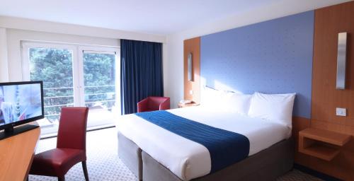 Habitación familiar con una cama doble y dos camas plegables individuales del hotel Ramada By Wyndham London North M1. Foto 5