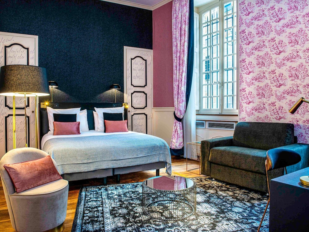 Habitación Privilege con una cama doble y un sillón del hotel Mercure Figeac Viguier du Roy