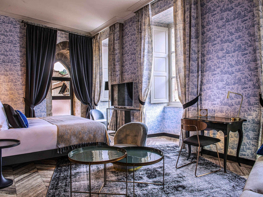 Habitación Privilege con una cama doble y un sillón del hotel Mercure Figeac Viguier du Roy. Foto 1