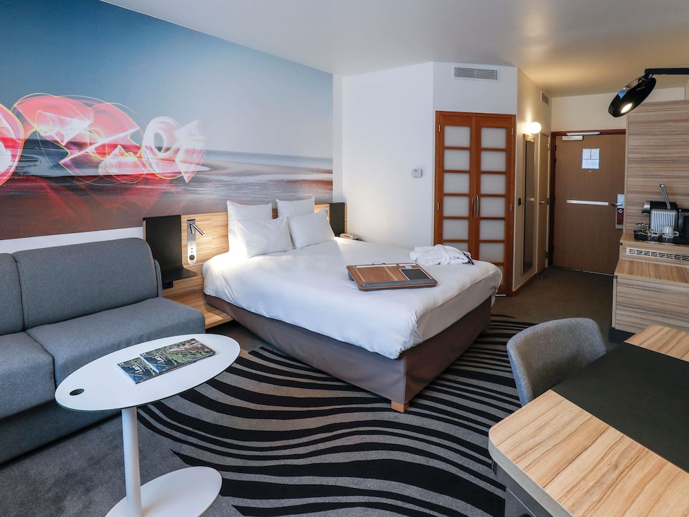 Habitación de categoría superior con una cama de matrimonio y un sofá del hotel Novotel Luxembourg Centre