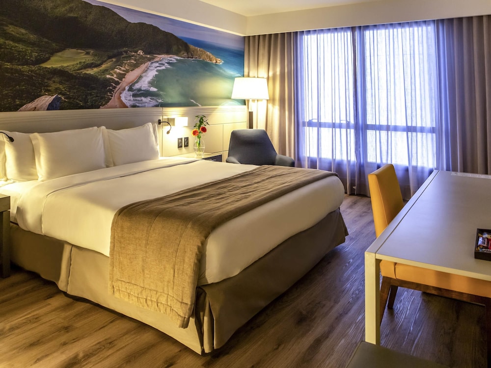 Habitación de categoría superior con una cama king size y vistas parciales al mar del hotel Novotel Florianópolis