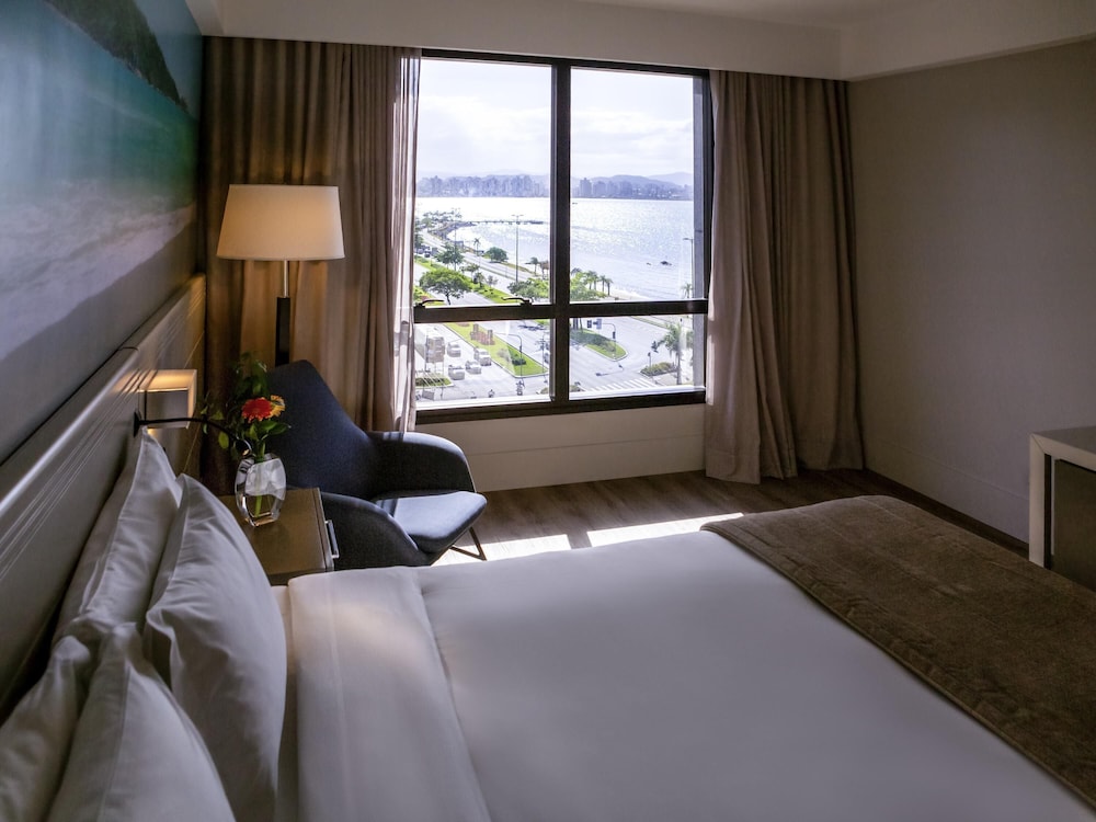 Habitación de categoría superior con una cama king size y vistas parciales al mar del hotel Novotel Florianópolis. Foto 2