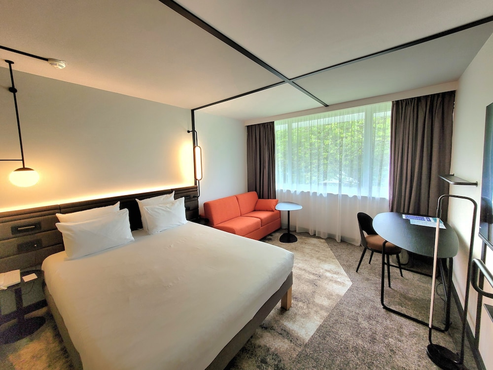 Habitación Superior con cama queen size y un sofá del hotel Novotel Lille Aeroport. Foto 3