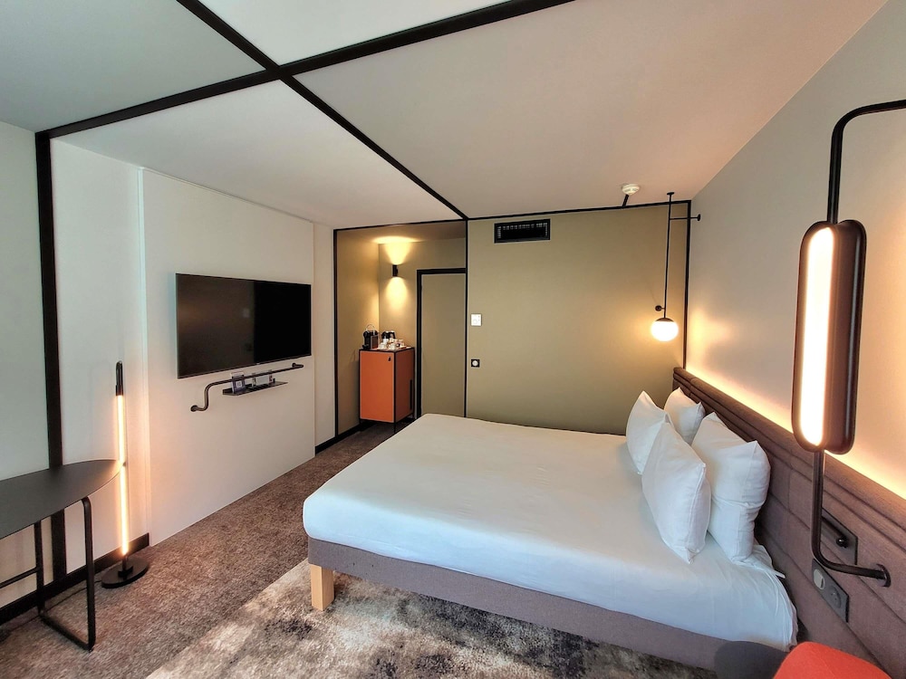 Habitación Superior con cama queen size y un sofá del hotel Novotel Lille Aeroport. Foto 5