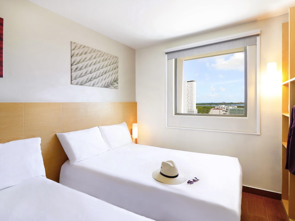 Una cama matrimonial con vista a la laguna, Caja fuerte, frigo - bar, cama matrimonial del hotel Ibis Cancun Centro. Foto 4