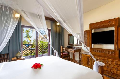 Habitación con cama grande y vistas parciales al mar del hotel Nungwi Beach Resort by Turaco. Foto 2