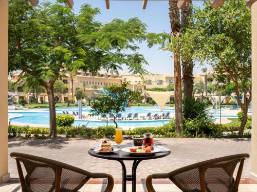 Habitación Deluxe con cama extragrande y vistas al jardín y a la piscina del hotel Movenpick Cairo Media City