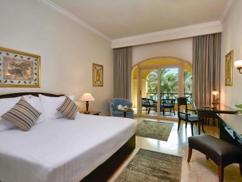 Habitación Deluxe con cama extragrande y vistas al jardín y a la piscina del hotel Movenpick Cairo Media City. Foto 1